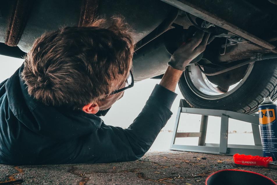 employee fixing vehicle engine at Custom Complete Automotive