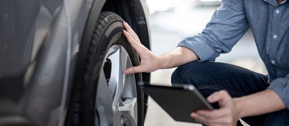 person inspecting tire tread on vehicle