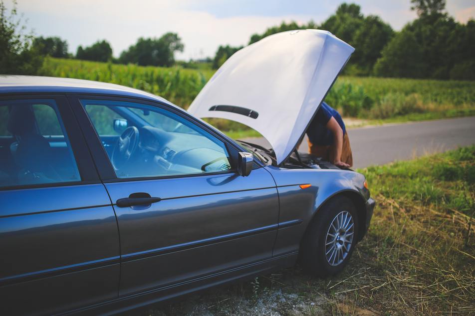 man checking car battery issue during summer