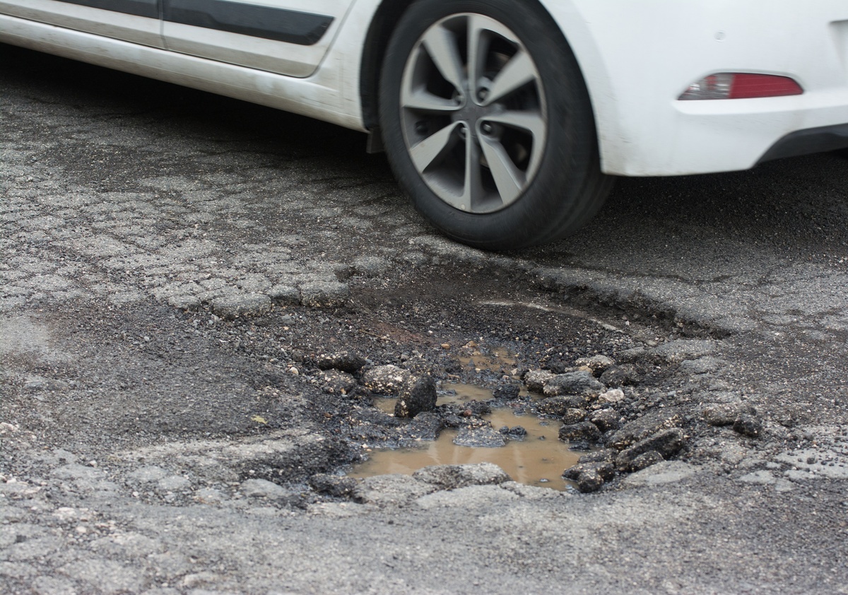 car driving over pothole and receiving pothole damage