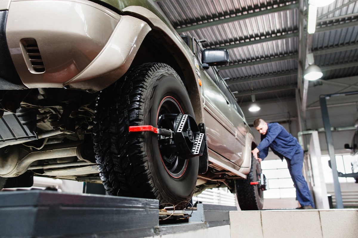 mechanic performing wheel alignment on vehicle