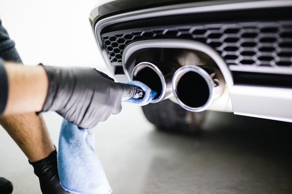 auto mechanic cleaning car exhaust system