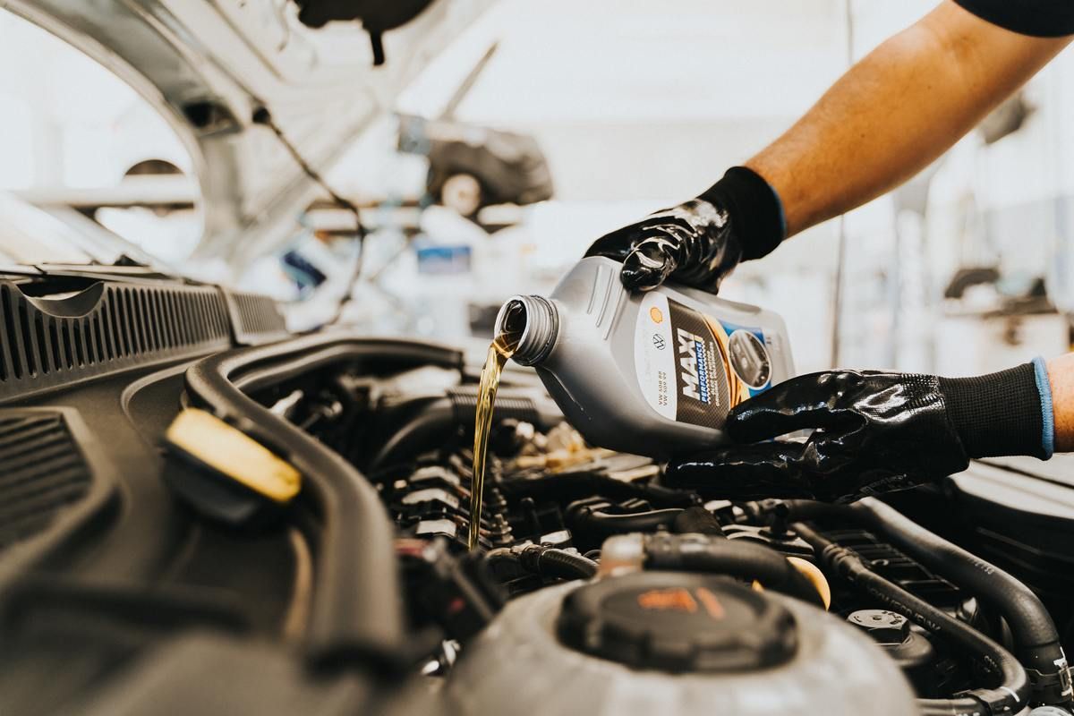 mechanic adding oil to vehicle to fix low oil pressure