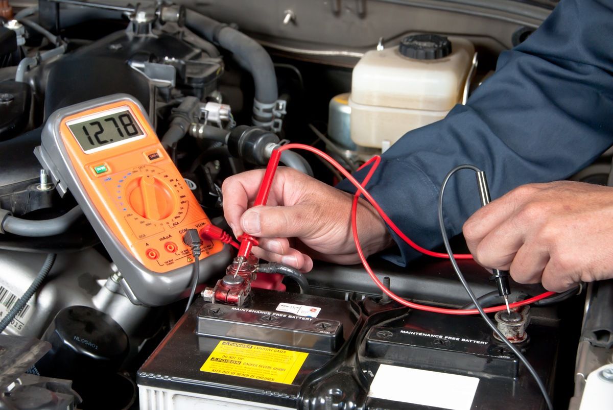 car mechanic checking charge on battery