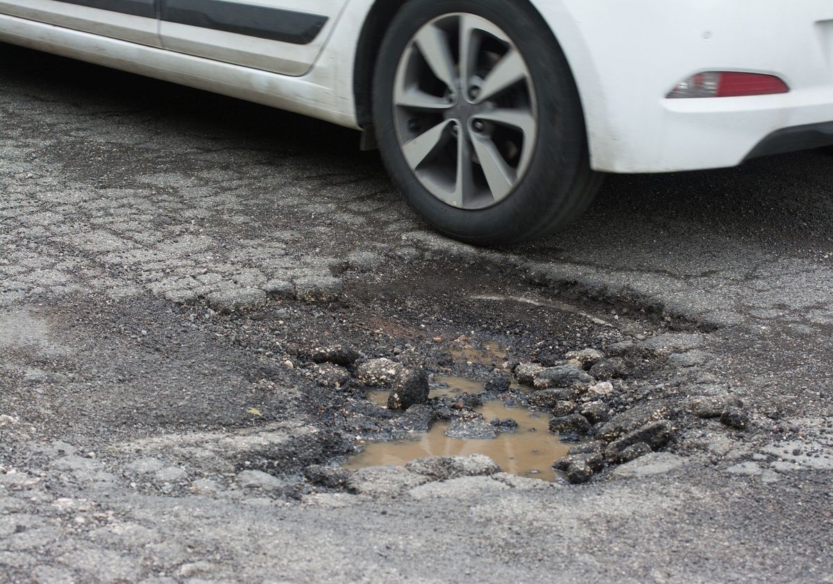 car driving over pothole and receiving pothole damage